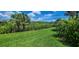 Manicured back yard with pristine grass and tropical landscaping overlooking natural surroundings at 15048 Spanish Point Dr, Port Charlotte, FL 33981