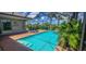 Inviting screened-in pool with spa, sun loungers, and tropical plants on a sunny day at 15048 Spanish Point Dr, Port Charlotte, FL 33981