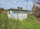 Small, weathered storage shed in overgrown yard at 11290 6Th Ave, Punta Gorda, FL 33955