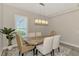 Modern dining room with wood table, neutral chairs, and stylish light fixture at 12424 Davie Ct, Venice, FL 34293