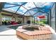 Screened pool and spa with brick coping and a red umbrella at 15658 Stuart Cir, Port Charlotte, FL 33981