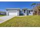 Newly built home features a gray exterior, white garage door, and well-manicured lawn at 308 Capatola St, Port Charlotte, FL 33948