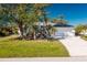 White house with a green lawn, palm trees, and a driveway at 217 Rotonda Cir, Rotonda West, FL 33947