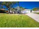 White house with a green lawn, palm trees, and a driveway at 217 Rotonda Cir, Rotonda West, FL 33947