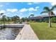 Spacious backyard patio with a canal view, walkway, and lush landscaping at 15576 Aldama Cir, Port Charlotte, FL 33981