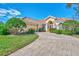 Tan one-story house with tile roof, landscaping, and paved driveway at 3335 Pennyroyal Rd, Port Charlotte, FL 33953