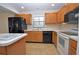 Kitchen features wood cabinets, black appliances, and a breakfast bar at 412 Cypress Forest Dr, Englewood, FL 34223