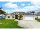 Single-story home with a two-car garage and well-manicured lawn at 665 Rotonda Cir, Rotonda West, FL 33947