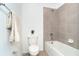 Well-lit bathroom features tiled shower and tub, toilet with a cute vase, and towel bar at 19524 Fishhawk Trl, Venice, FL 34293