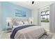 Light bedroom featuring tufted headboard, stylish lamps, and a serene blue accent wall with landscape artwork at 19536 Fishhawk Trl, Venice, FL 34293