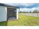 A side view of the screened in patio and yard featuring well maintained lawn and a white wooden fence at 19536 Fishhawk Trl, Venice, FL 34293
