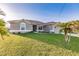 Single-story home with gray exterior, landscaped lawn, and palm trees at 263 W Pine Valley Ln, Rotonda West, FL 33947