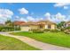 Exterior view of a yellow house with a landscaped lawn and driveway at 1985 Coconut Palm Cir, North Port, FL 34288