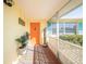 Inviting porch with terracotta tile floor, orange door and potted plants at 42 Caroll Cir, Englewood, FL 34223