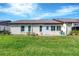 Rear view of house showing patio, landscaping, and grassy area at 618 Deerwood Ave, Englewood, FL 34223