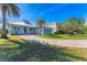 Single-story home with a metal roof, a paved driveway, and a large yard at 8025 Weyers Ct, Englewood, FL 34224