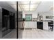 Bright kitchen features white cabinets, a tile floor, and stainless steel appliances at 10127 Peach Ave, Englewood, FL 34224