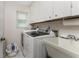 Functional laundry room with washer, dryer, utility sink, and storage cabinets at 10127 Peach Ave, Englewood, FL 34224