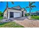 Tan house with orange shutters, a white garage door, and a brick driveway at 2148 La Palma Ave, Port Charlotte, FL 33953