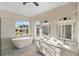 Modern bathroom featuring a soaking tub, dual vanity, and large window at 10030 Eagle Preserve Dr, Englewood, FL 34224