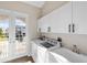 Laundry room with white cabinets, washer, dryer, and access to a private balcony at 10030 Eagle Preserve Dr, Englewood, FL 34224