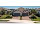 Two-car garage, light beige exterior, brown tile roof, and landscaped lawn at 11249 Mc Dermott Ct, Englewood, FL 34223