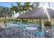 Relaxing patio area with thatched roof cabana and white tables at 11249 Mc Dermott Ct, Englewood, FL 34223