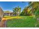 Spacious backyard with lush grass, palm trees, and screened enclosure at 2 Marker Rd, Rotonda West, FL 33947