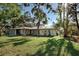 Exterior view of a home with a lush green lawn and mature trees at 1155 Forest Dr, Englewood, FL 34223