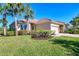 Exterior view of a single-story house with tile roof, landscaping and a paved driveway at 13091 Creekside Ln, Port Charlotte, FL 33953