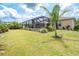 Expansive backyard with a well-maintained lawn, mature palm trees, and screened lanai with a covered patio set at 14010 San Domingo Blvd, Port Charlotte, FL 33981