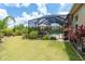 Lush backyard with manicured lawn, tropical landscaping, and screened lanai leading to the sparkling pool at 14010 San Domingo Blvd, Port Charlotte, FL 33981