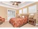 Inviting bedroom features a ceiling fan, shuttered windows, and a comfortable bed with tropical-themed bedding at 14010 San Domingo Blvd, Port Charlotte, FL 33981