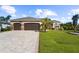 Charming single-story home with a three-car garage, manicured lawn, and paver driveway at 14010 San Domingo Blvd, Port Charlotte, FL 33981