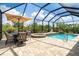 Beautiful screened pool with a waterfall feature, hot tub and an outdoor dining area shaded by an umbrella at 14010 San Domingo Blvd, Port Charlotte, FL 33981