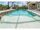 Inviting screened pool with a rock waterfall feature and steps to the outdoor kitchen at 14010 San Domingo Blvd, Port Charlotte, FL 33981