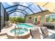 Relaxing screened pool area with hot tub, waterfall, outdoor furniture, and summer kitchen at 14010 San Domingo Blvd, Port Charlotte, FL 33981