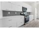 White shaker cabinets, gray tile backsplash, and stainless steel appliances at 15384 Hennipen Cir, Port Charlotte, FL 33981