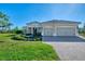 Tan house with tile roof, two car garage, and lush landscaping at 26852 Faldo Ln, Englewood, FL 34223