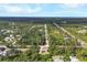 Drone view highlights the property's location within a serene neighborhood amidst green trees and a road at 4036 Elvington Rd, Port Charlotte, FL 33981