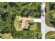 Aerial view showcases a well-maintained house with a driveway amidst lush greenery and a quiet street at 4036 Elvington Rd, Port Charlotte, FL 33981