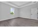 A modern bedroom features tray ceilings, gray walls, wood floors, and a bright window view at 7320 Freeberg Cir, Port Charlotte, FL 33981