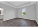 Bright bedroom featuring gray walls, wood floors, tray ceilings, and a window with a green view at 7320 Freeberg Cir, Port Charlotte, FL 33981