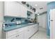 White kitchen cabinets, light blue countertops and view down the long galley kitchen at 7346 Regina Dr, Englewood, FL 34224