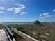 A wooden boardwalk provides access to the beach under a clear blue sky and wispy white clouds at 13104 Via Cassia, Placida, FL 33946