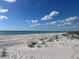 A sandy beach stretches out to the sea under a clear blue sky dotted with fluffy white clouds at 13104 Via Cassia, Placida, FL 33946