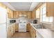 Kitchen with light wood cabinets, white appliances, and a double sink at 1531 Placida Rd # 1-204, Englewood, FL 34223