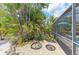 View of tropical backyard plants and landscaping elements adjacent to the screened-in pool area at 15375 Taurus Cir, Port Charlotte, FL 33981