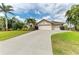 Elegant home showcasing a spacious three-car garage and long driveway, enhanced by lush landscaping and palm trees at 15375 Taurus Cir, Port Charlotte, FL 33981