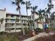 Exterior view of a three-story condo building with balconies, surrounded by palm trees and a picnic area at 1751 Beach Rd # 204, Englewood, FL 34223